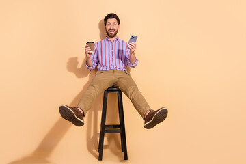 Photo of playful and handsome entrepreneur having coffee break watching videos smartphone isolated...