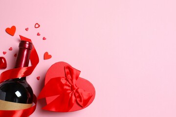 Beautiful gift box, bottle of red wine and hearts on color background