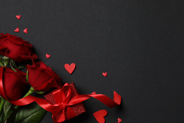 Beautiful red roses, gift box and hearts on black background