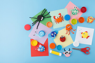Animal crafts using bottle caps and colored paper on a white background. Flat lay composition with fish, octopus, elephant, spider, crab, and turtle designs. DIY children activity and recycling