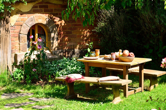 MATAMATA, NEW ZEALAND - January 29, 2017: Garden table set with moulage food and dinnerware in front of a red brick hobbit house at Hobbiton Movie Set