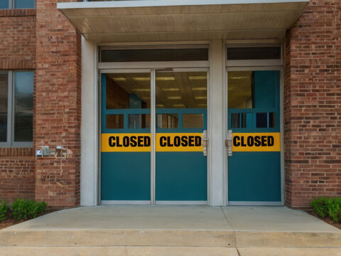 Puertas de colegio con una banda en la puerta que dice cerrado
