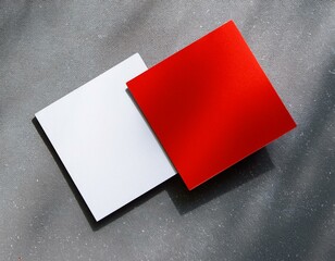 White and red square business card mockups diagonally placed on a neutral grey concrete background with soft shadows, offering a clean flat lay design