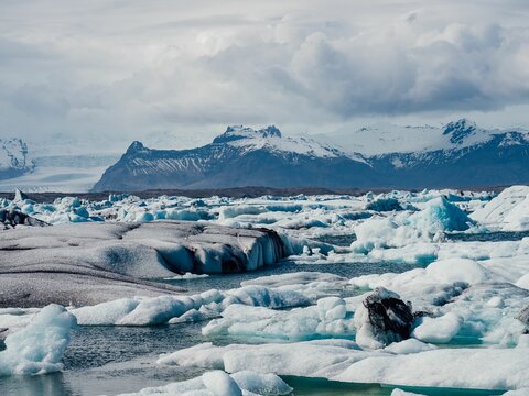 Scenic view of icy landscape with floating icebergs and mountains in Jokulsarlon Glacier Lagoon.