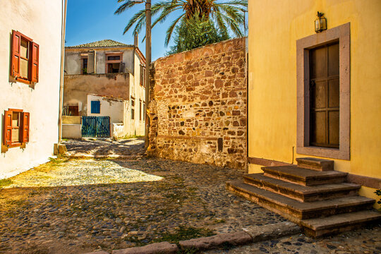 Charming cobblestone street with rustic houses and vibrant sunlight in Edremit.