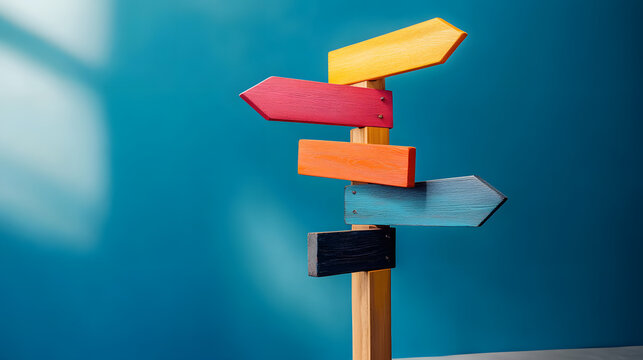Wooden post with vibrant directional signs against a blue background, symbolizing choices, directions, and decision-making.