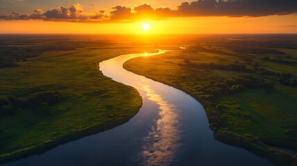 Fototapeta premium A highly detailed aerial photograph of a meandering river cutting through golden fields, reflecting the soft glow of the setting sun.