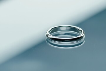 The image captures a sleek platinum band with a minimalist mirror finish, emphasizing its modern simplicity and refined elegance in a serene blue setting.