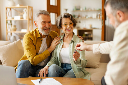 Male real estate agent giving keys to happy senior couple buyers, spouses celebrate apartment purchase from relator or broker. Rental concept - Powered by Adobe