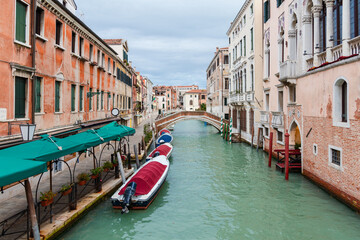 Obraz premium Venetian Canal with Boats and Small Bridge