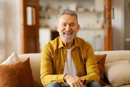 Portrait of happy older retired man laughing, looking at camera, enjoying video call or distant communicating with friends