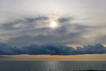 Dramatic sky above the sea glittering in pale sunlight