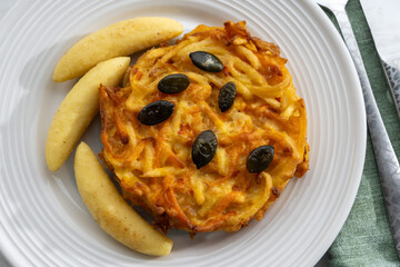 Pumpkin grated roasted patties, rosti or latkes and Fingernudel, finger potato noodle, dumplings decorated with pumpkin seeds
