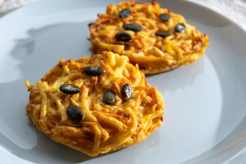 Pumpkin grated roasted patties, rosti or latkes, made fron squash and potato decorated with pumpkin seeds