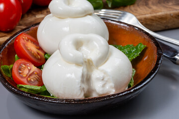 Cheese collection, eating of fresh soft white burrata cheese ball made from mozzarella and cream from Apulia, Italy, close up