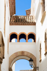 Delivery man riding a scooter in a narrow street with white houses in sitges, spain
