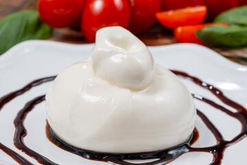 Cheese collection, fresh soft white burrata cheese ball made from mozzarella and cream served with balsamic vinegar from Modena, Italy, close up
