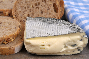 Morceau de fromage français Montbriac avec des tranches de pain aux graines en gros plan