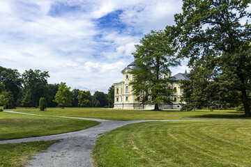 A beautiful and well-kept castle garden. Castle building in the background behind the trees. Historic building. A castle with a castle garden.