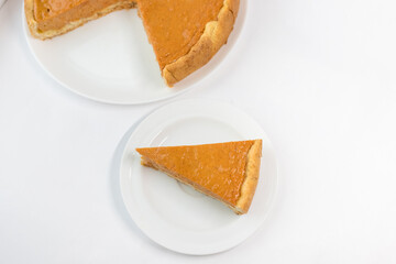 A piece of pumpkin pie with caramel sauce on the white background. Traditional cake. Ready to eat. Cooking concept. Halloween time