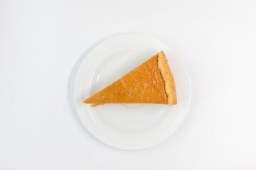 A piece of pumpkin pie with caramel sauce on the white background. Traditional cake. Ready to eat. Cooking concept. Halloween time