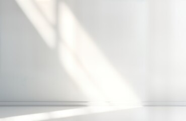 Empty indoor studio space with white walls, floor. Sunlight streams in through window creating soft shadows on wall. Minimalist, modern design perfect for product presentations or text insertions.