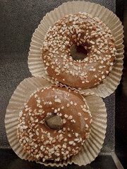 Caramel glazed donuts topped with crushed nuts in paper wraps. Sweet dessert