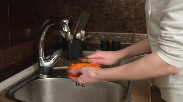 Woman peels carrot with knife close up. Female cleans carrot with knife. Close up woman using knife to peel carrot