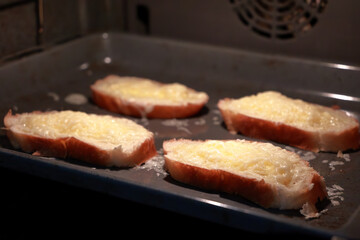  Slices Of Cheese Toast Baking On Tray In Oven.