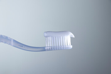 White toothpaste on a White toothbrush with White bristles close-up on a gradient white-gray background