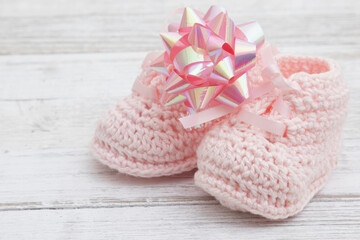 Pink baby booties with a bow on wood