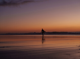 silhouette of person walking on the beach at sunset