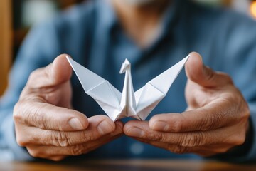 Obraz premium An intricately folded paper swan is showcased in a person's hands, emphasizing the delicate beauty of origami and the fine art of handmade creations in a serene environment.