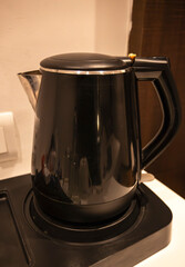 An electric kettle is placed on the hotel room desk in the living room. This convenient appliance allows guests to prepare hot beverages easily.
