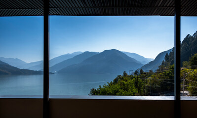 A view from the balcony frames the mountains and lake, shrouded in blue mist during sunrise. This...