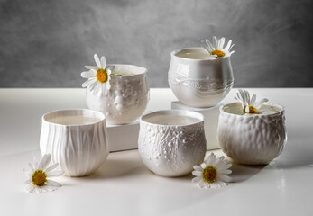 Porcelain white cups with chamomile flowers on a light table