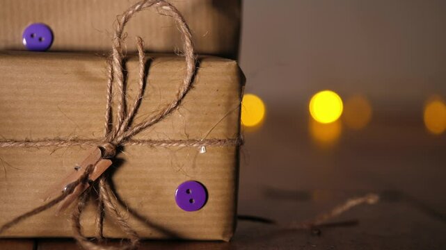Gift wrapped in brown paper and string with Christmas lights bokeh background