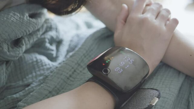 Close-up of a person wearing a health monitoring device on their wrist, showcasing vital signs and health metrics. The device offers insights into heart rate and overall wellness.
