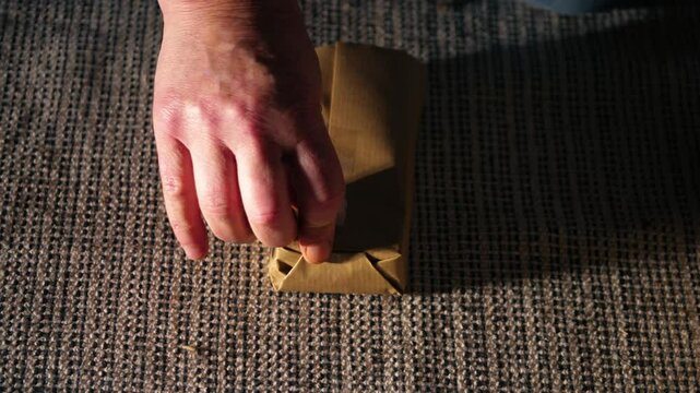 Hands wrapping gift in brown paper