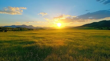 Obraz premium Breathtaking Golden Sunset Over Vast Countryside Meadow With Mountains Silhouetted On The Horizon