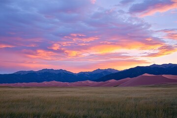 Obraz premium A magical sunset unfolds over the serene dunes with the silhouette of distant mountains, capturing a vista of enchanting natural beauty that instills tranquility.