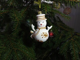 New Year's decoration in the form of a white snowman on the branches of a Christmas tree. Winter...