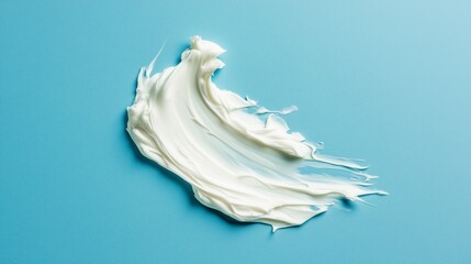 Fototapeta premium Thick small patch of conditioner in swoosh shape on blue solid background.