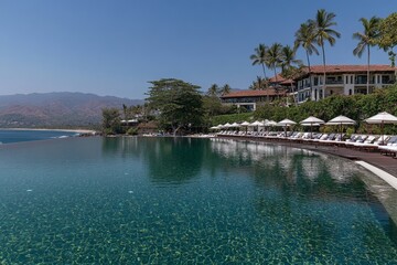 An infinity pool at a beachfront resort, with crystal-clear water and palm trees swaying in the background