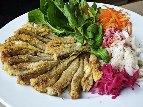 Hamsi Tava is a traditional Turkish balık seafood dish made from hamsi or fried anchovies, served with salad, onions, and parsley