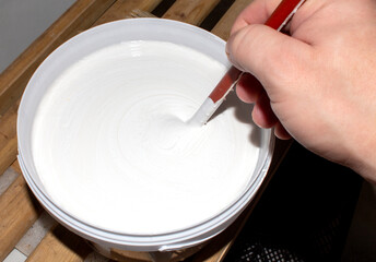 Acrylic white matte paint in a jar.Stir in the acrylic paint.Acrylic paint background.
