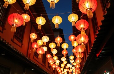 Chinese new year celebration in city street. Illuminated lanterns in red, yellow hang from buildings. Traditional craft, culture. Night time scene with no people. Exterior view of historic buildings.