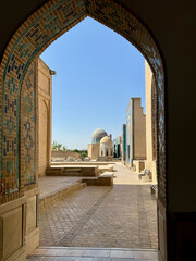 Fototapeta premium Historic Courtyard with Mosaic Arch and Dome under Blue Sky