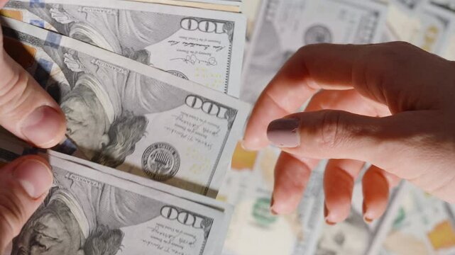 Counting a stack of money to give to a woman, with a ten-dollar bill being handed over in motion.