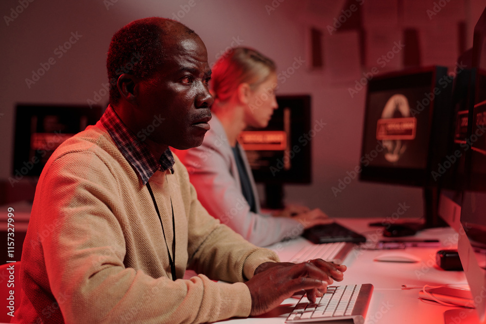 Aufkleber Side view of serious mature security guard trying to solve technical problem while sitting in front of computer screen